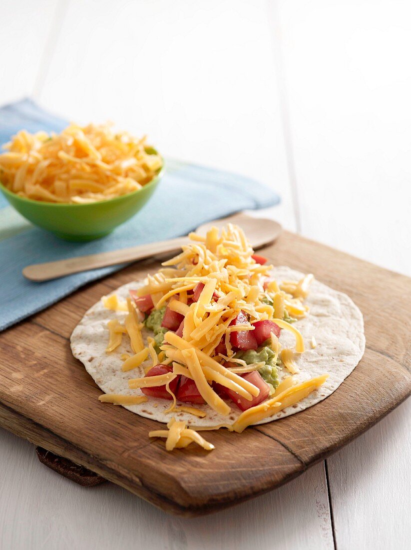 Tortilla with tomatoes, guacamole and cheddar cheese