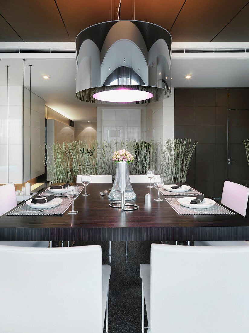 Designer hanging lamp with a black shade over a set dining table