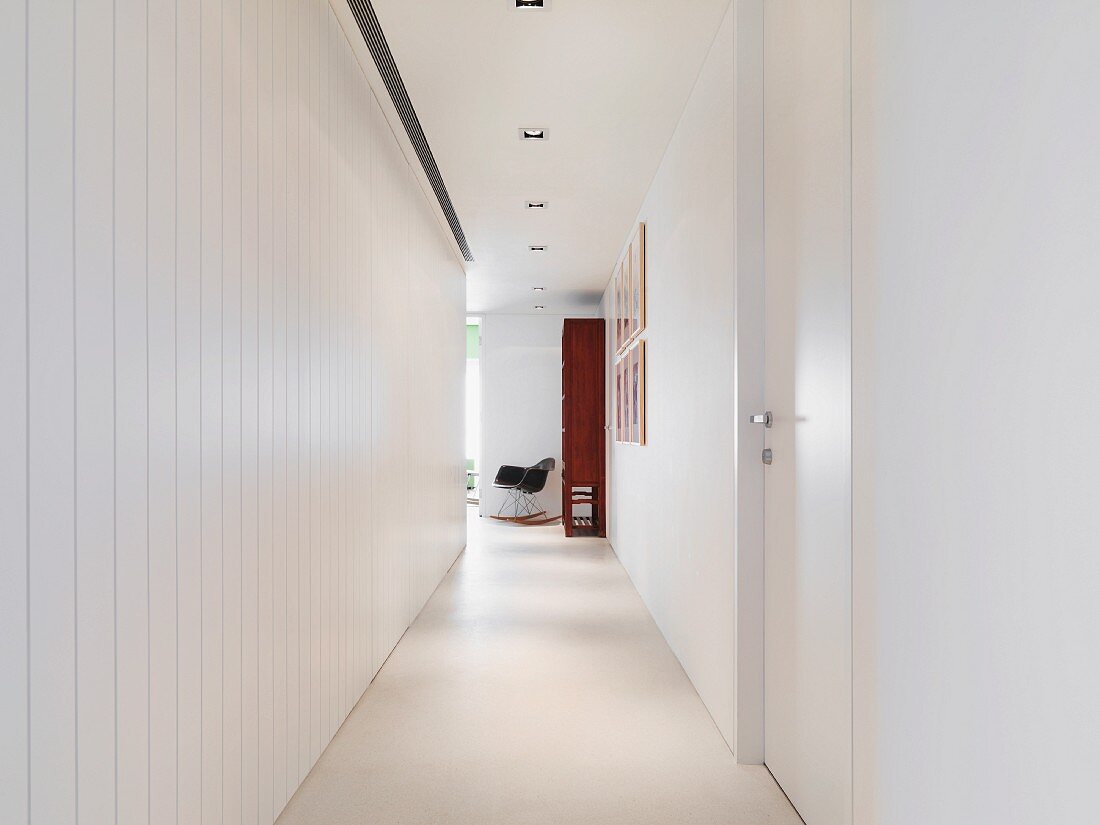 Narrow hallway with suspended ceiling and white lacquer wood wall paneling