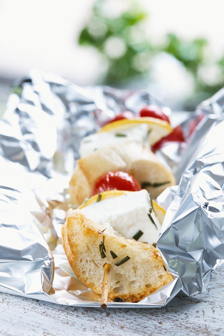 A grilled bread, feta and tomato kebab in tin foil