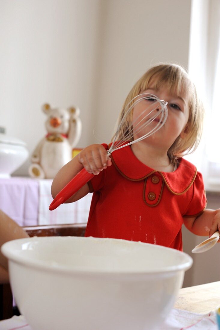 Young girl playing with whisk