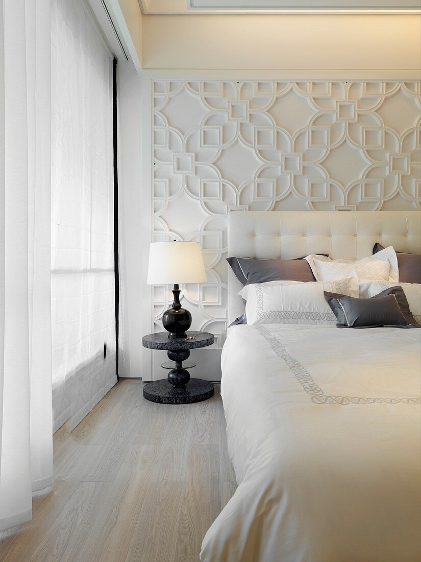 Klassisch modernes Schlafzimmer mit Bett vor reliefartig gestalteter Wand