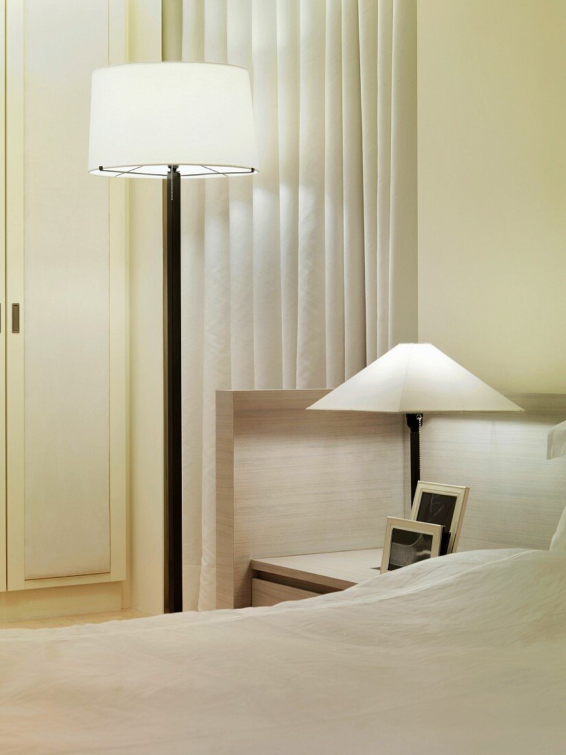 Minimalistischer Schwarzweiss-Look im Schlafzimmer mit Stehlampe und Tischlampe auf integriertem Nachttisch