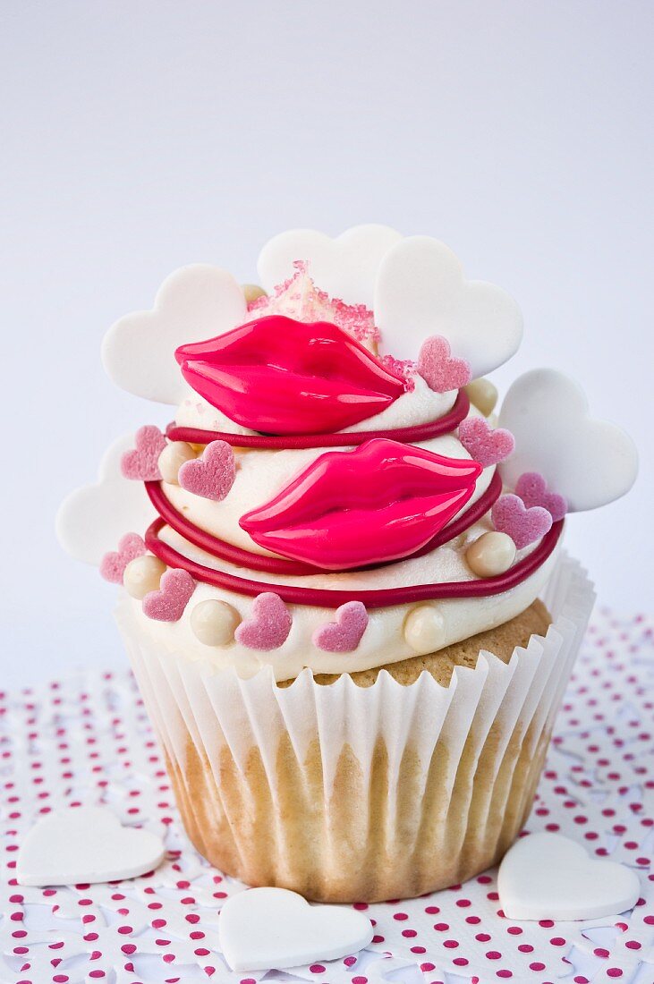 A cupcake decorated with red lips and sugar hearts for Valentine's Day