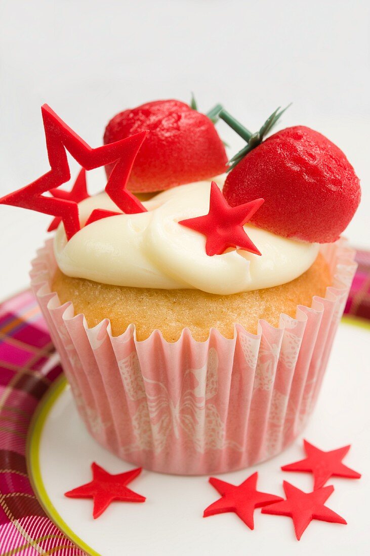 A cupcake decorated with marzipan strawberries and red stars