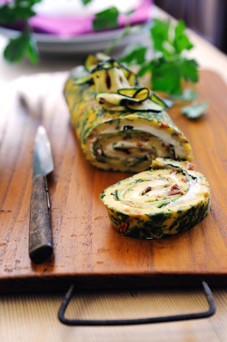 Herb and sun dried tomato omelet roulade filled with ham, cheese and courgette