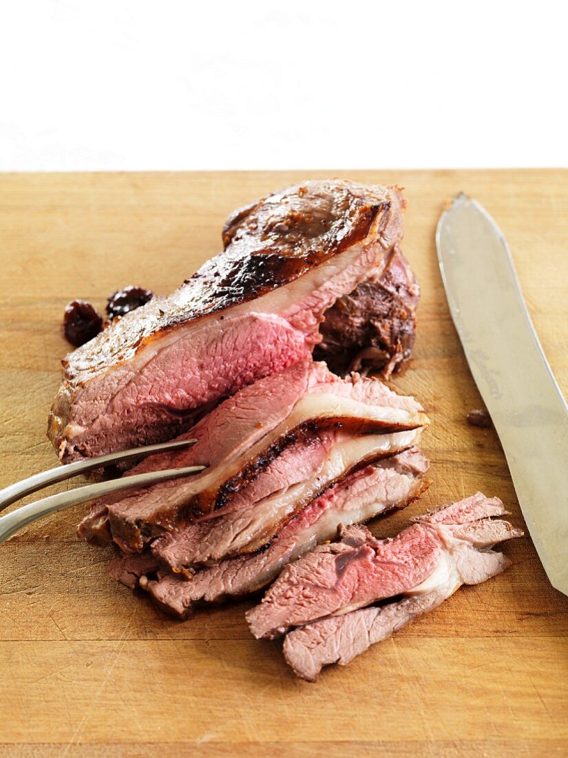 Roast lamb, sliced, on a choping board