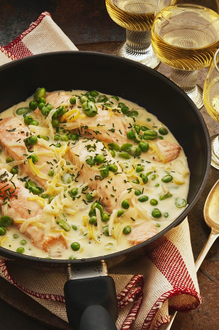 Salmon with a creamy sauce and fresh herbs in a pan