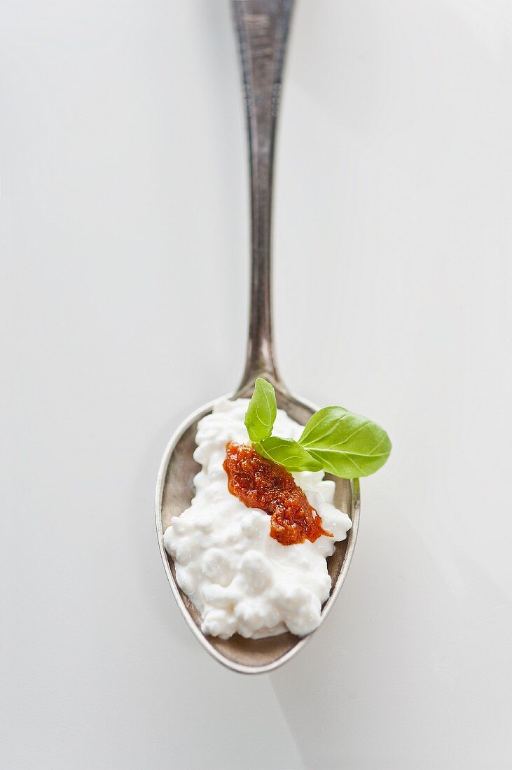 A spoonful of cottage cheese with tomato sugo and basil