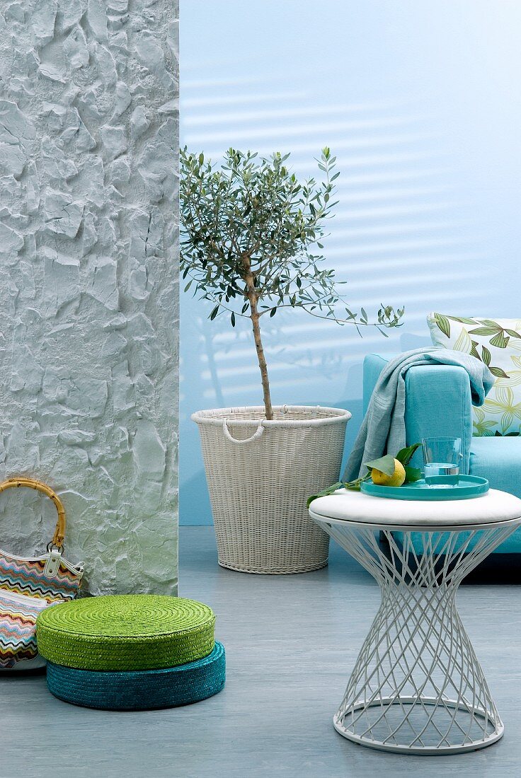 Interior in shades of aqua with sofa, side table & green and turquoise floor cushions