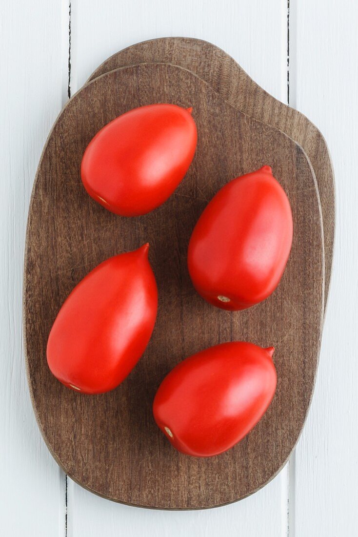 Four plum tomatoes on a chopping board