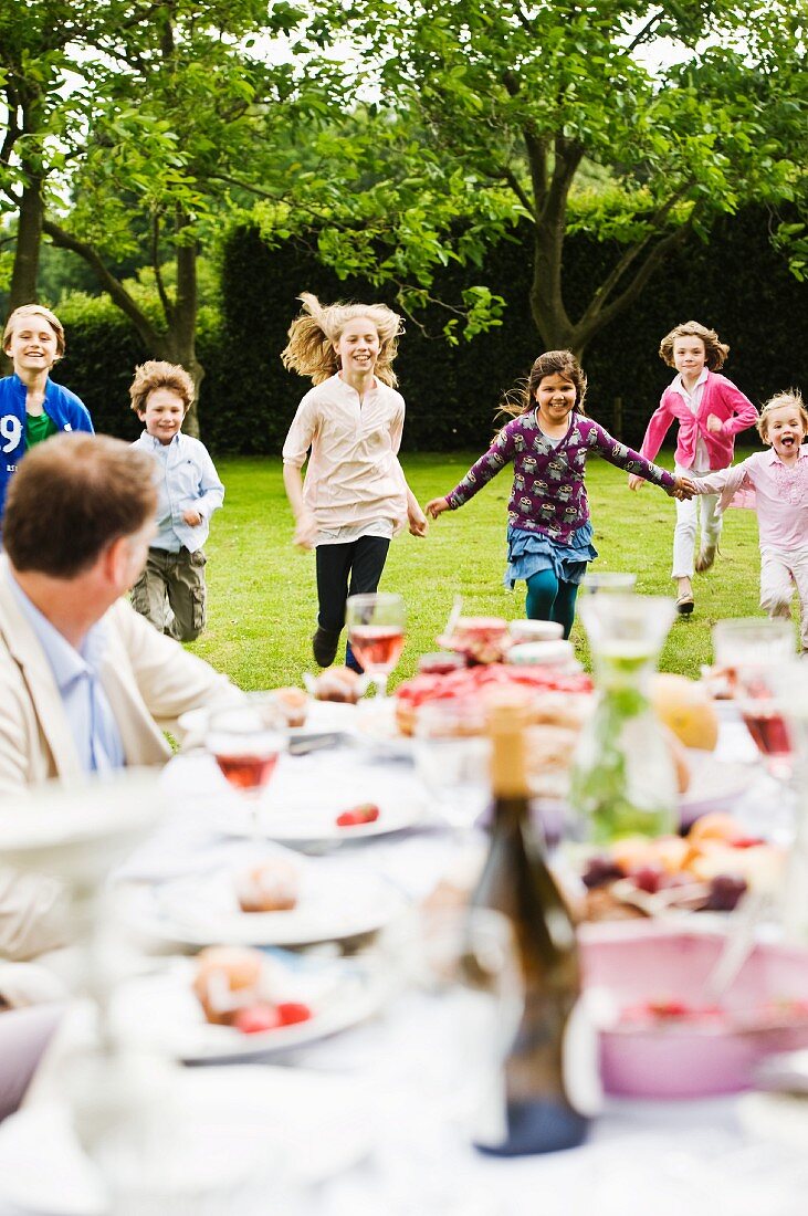 A garden party with children running about in the garden