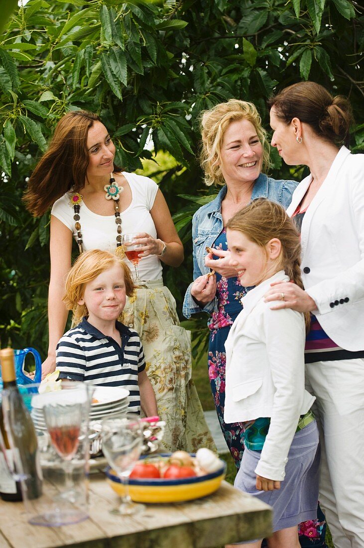 Children and adults standing by the buffet at a garden party