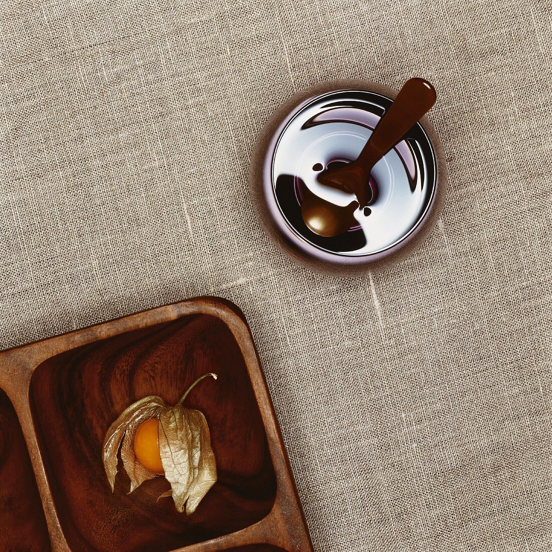 A physalis in a wooden dish and a glass of water