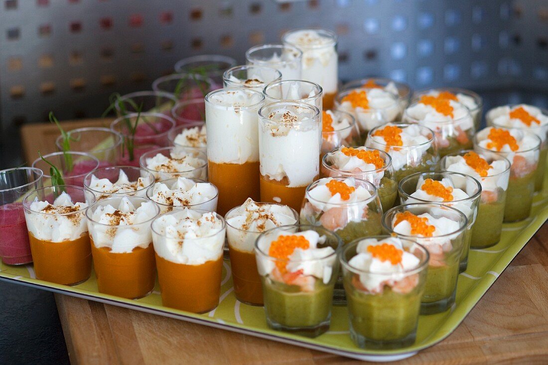 Various vegetable creams in glasses topped with whipped cream