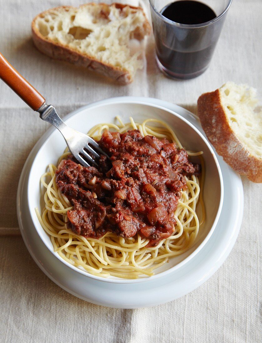 Bowl of Spaghetti Topped with a Ground Buffalo Tomato Sauce; Bread and Red Wine; From Above