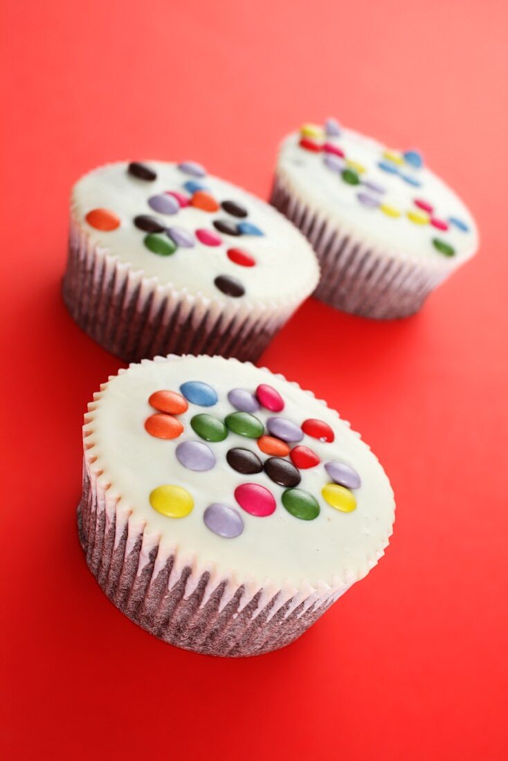White cupcakes decorated with coloured chocolate beans