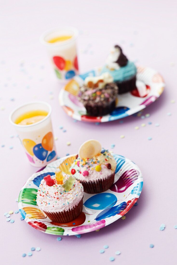 Bunte Cupcakes und Orangensaft für die Kinderparty