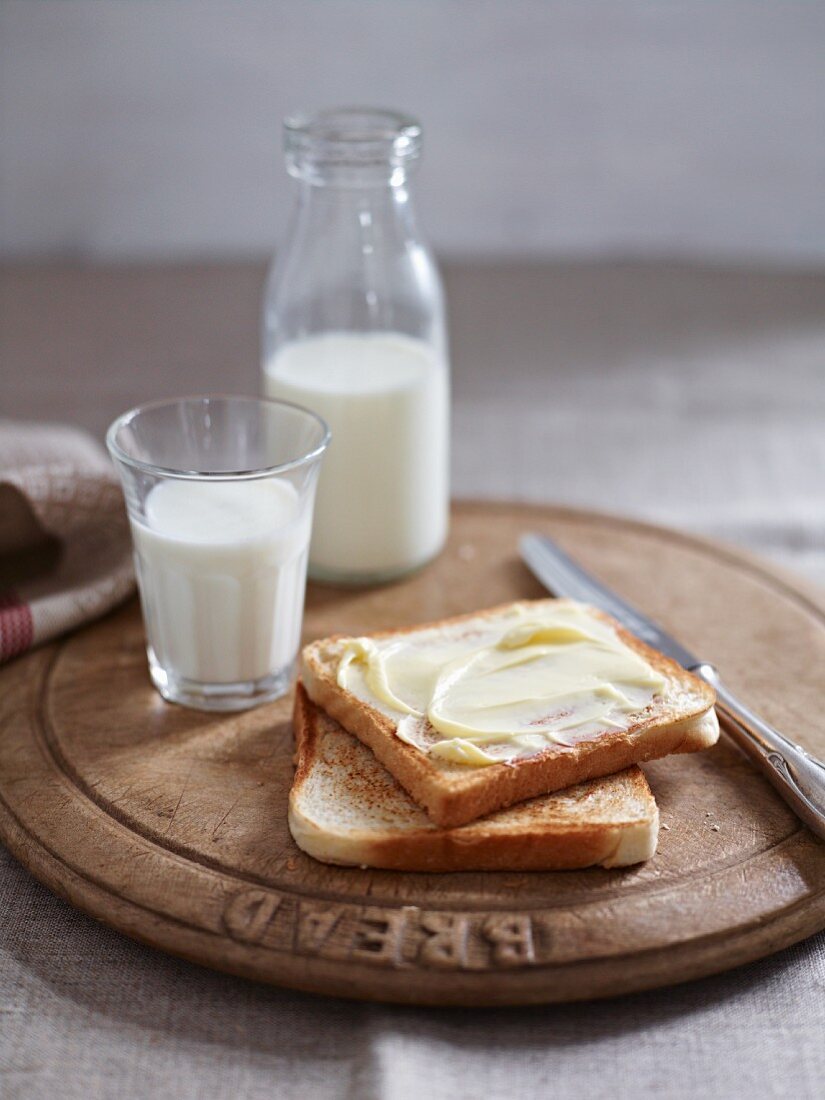 Buttered toast and milk on a wooden plate