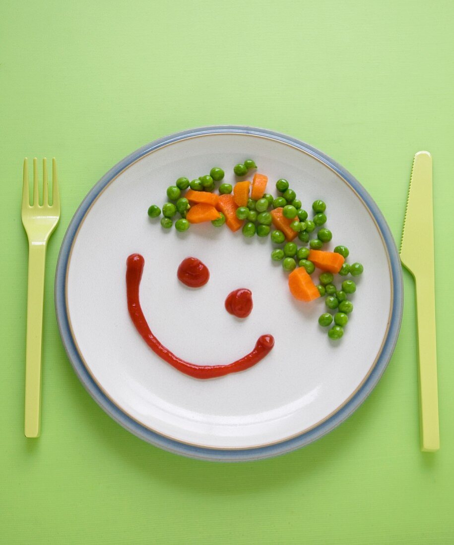 Teller mit Plastikbesteck & Gesicht aus Ketchup & Gemüse