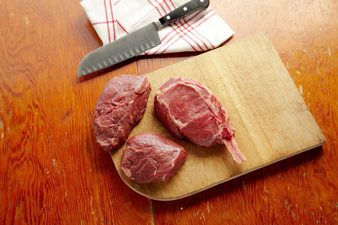 Raw Buffalo Sirloins on a Cutting Board with a Butcher Knife