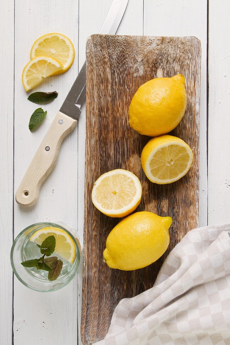 Lemons on a wooden board and a glass of lemon water