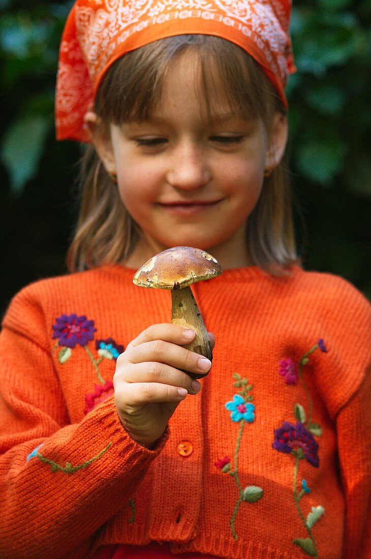 A girl holding a porcini mushroom