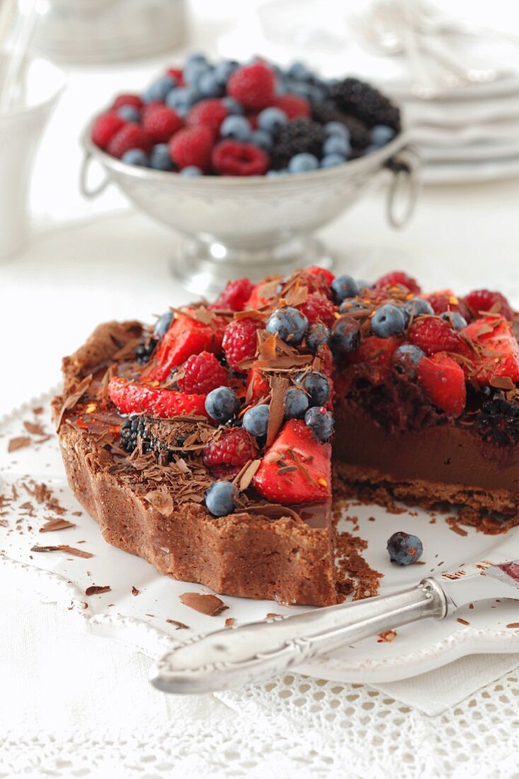 A chocolate cake topped with berries, sliced