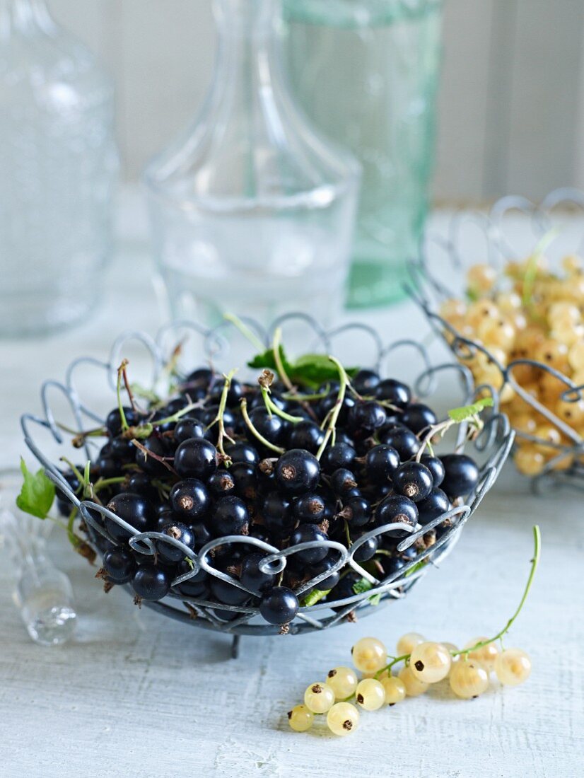 Blackcurrants and white currants in wire baskets