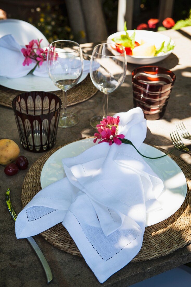 A white napkin with a flower decoration on a table laid in a rustic fashion