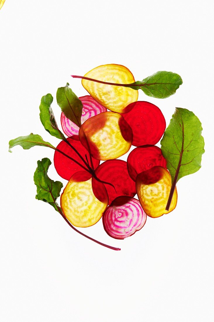 Thin Slices of Various Beets with Leaves on a White Background