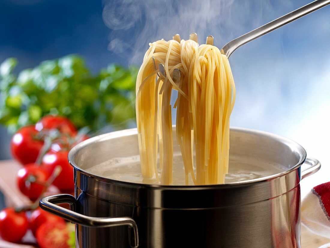 Gekochte Spaghetti mit Spaghettilöffel aus Topf heben
