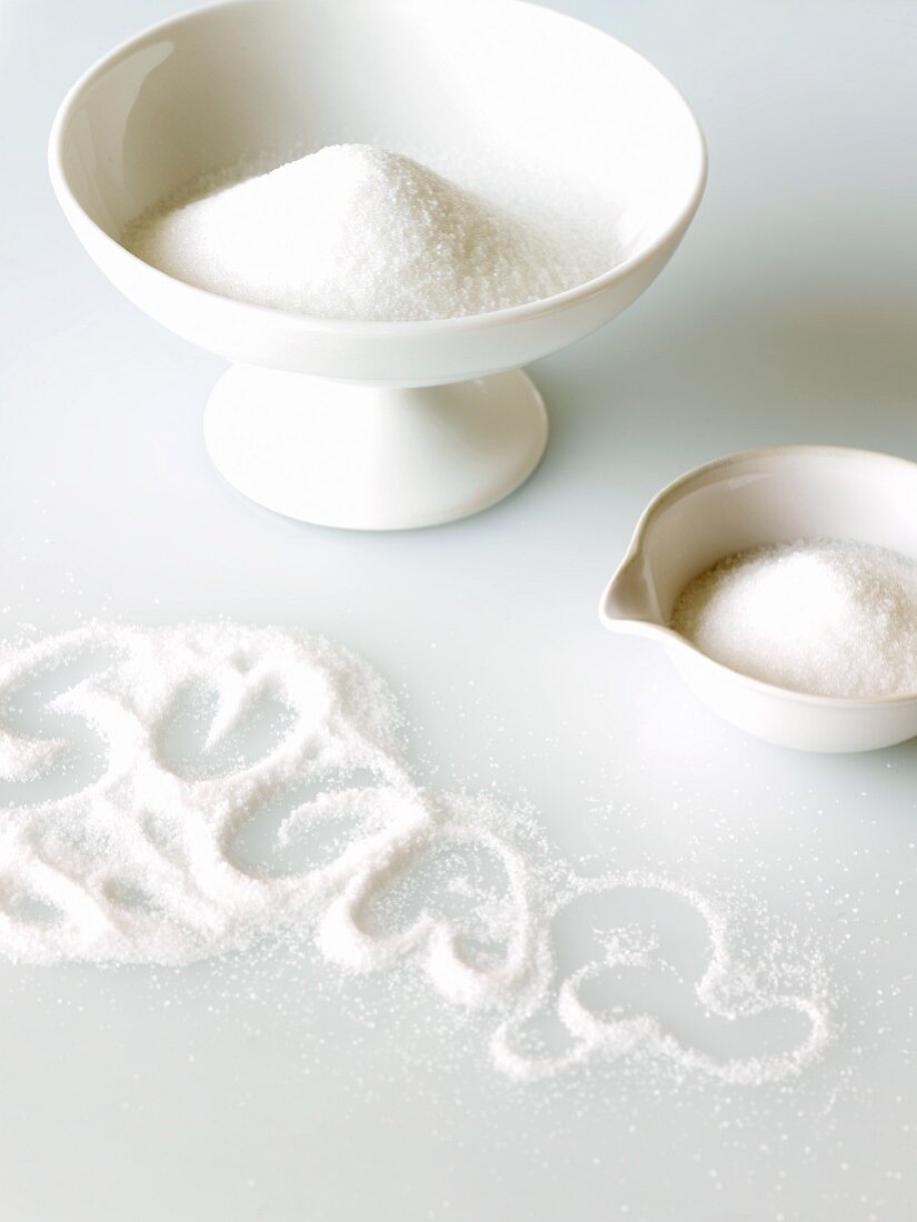 Two Bowls of Sugar and the Word Sugar Written in Spilled Sugar