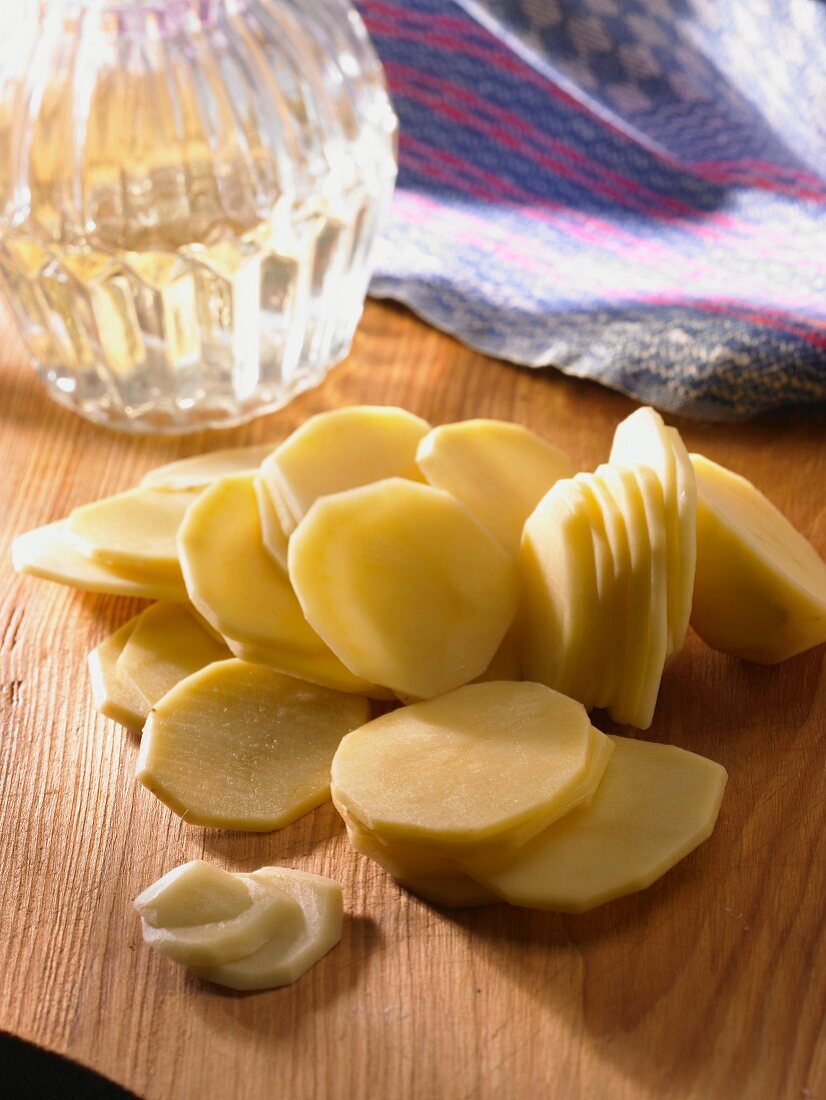 Raw potato slices on a wooden board