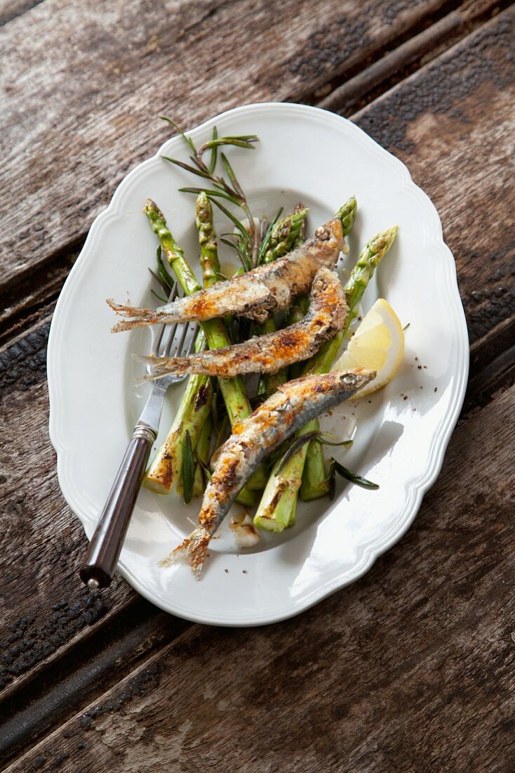 Grilled sardines on a bed of green asparagus with rosemary