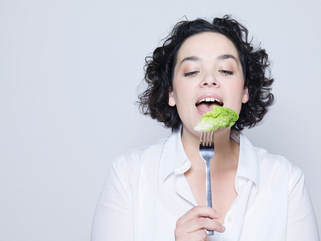 Woman holding lettuce leaf on fork