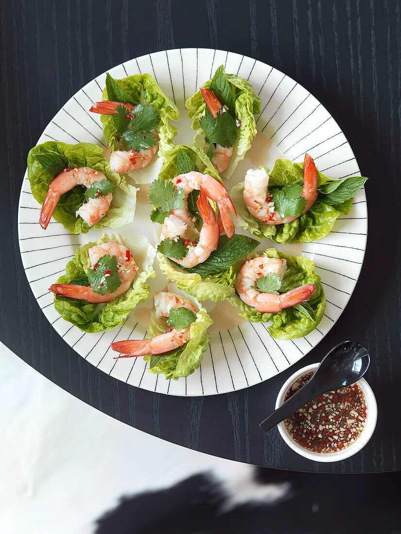 Prawns on lettuce leaves with fresh herbs and a spicy sauce