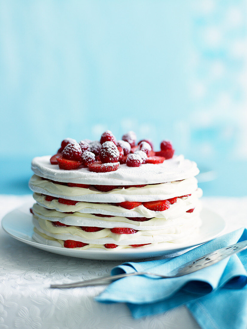 A layered meringue tart with strawberries and cream