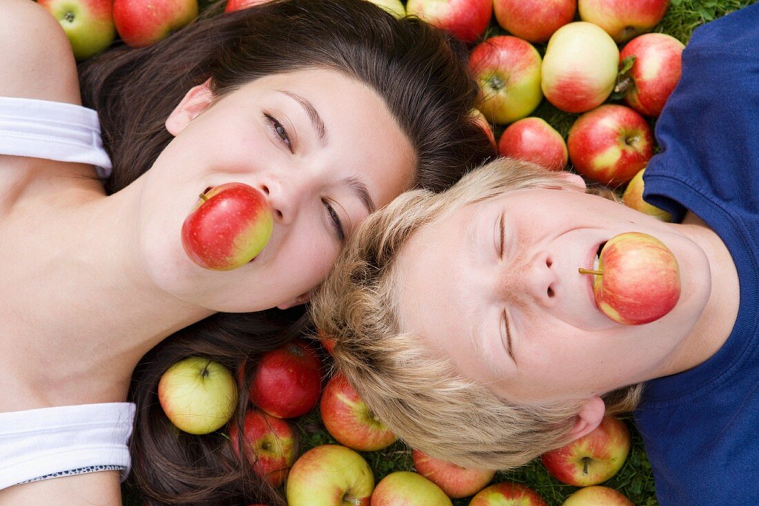 Mädchen und Junge mit Äpfeln im Mund