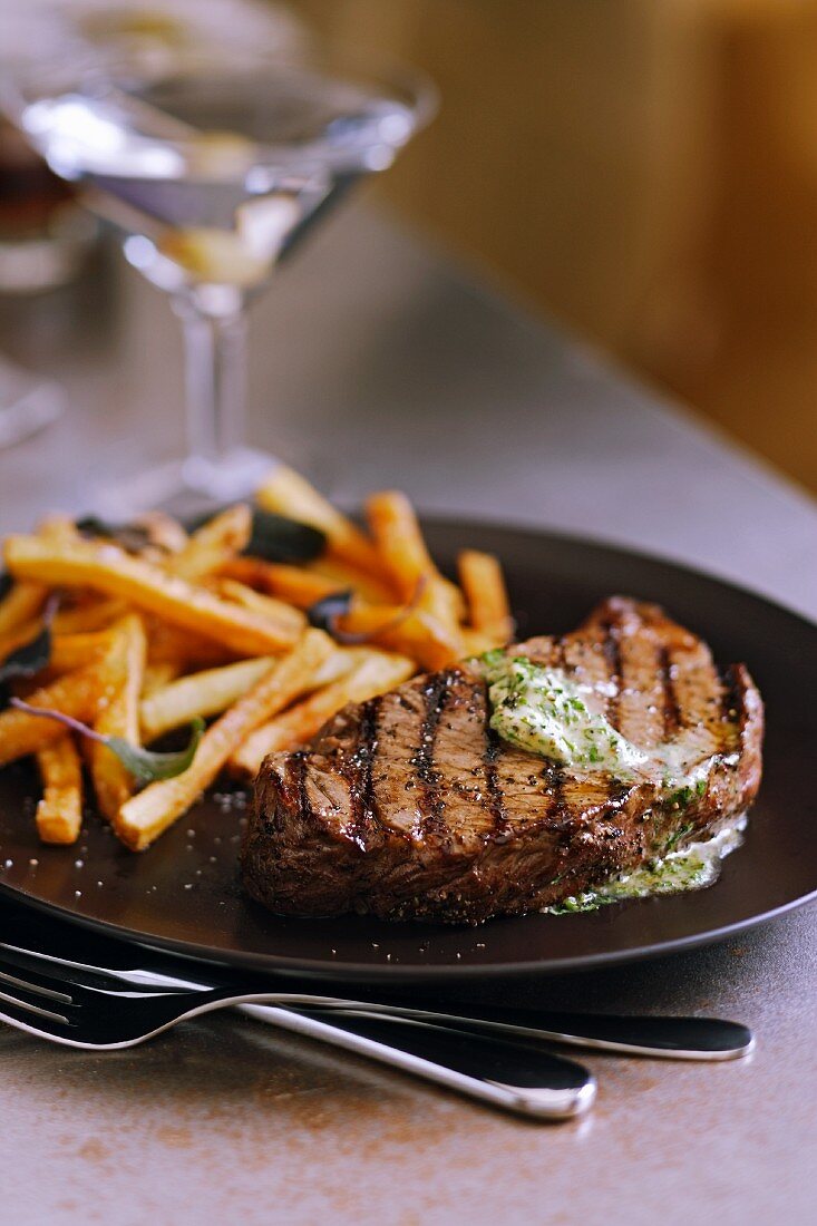 Gegrilltes Rindersteak mit Kräuterbutter und Pommes frites