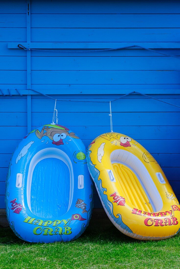 Zwei Schlauchboote an einer blauen Holzwand