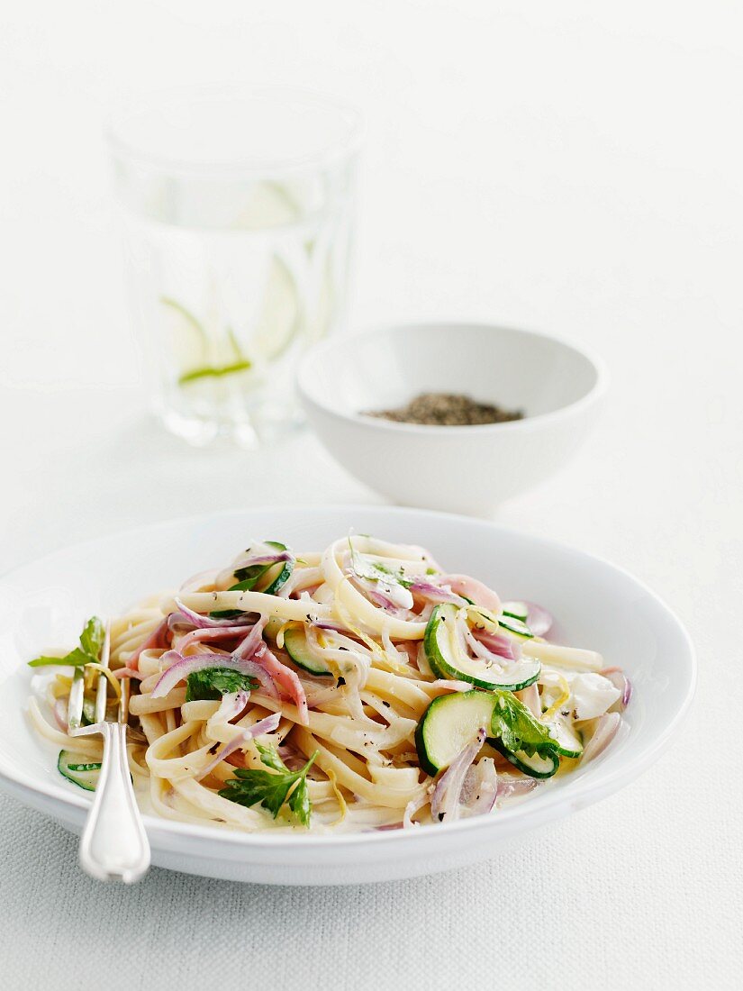 Ribbon noodles with strips of ham, zucchini and red onion