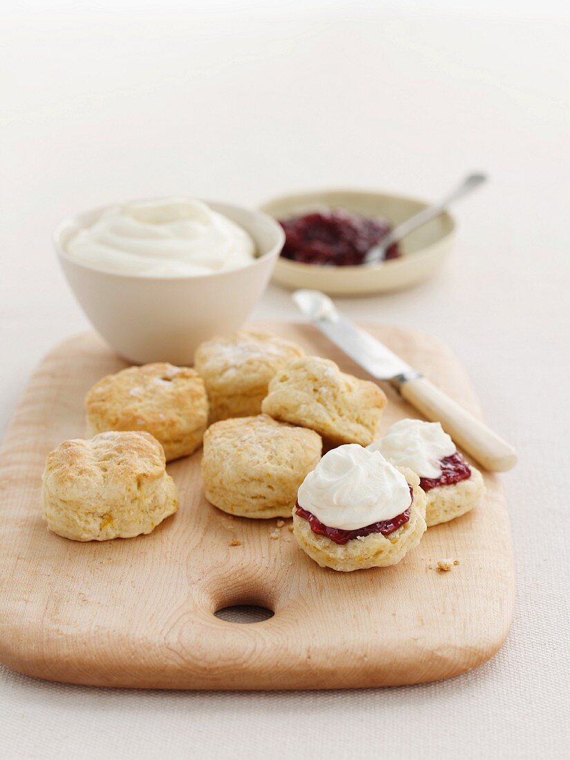 Scones with clotted cream and marmalade on a wooden board