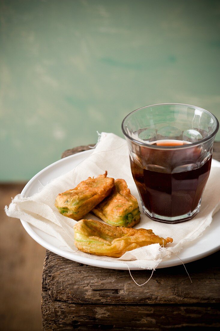Fried zucchini blossoms on a plate with a glass of red wine