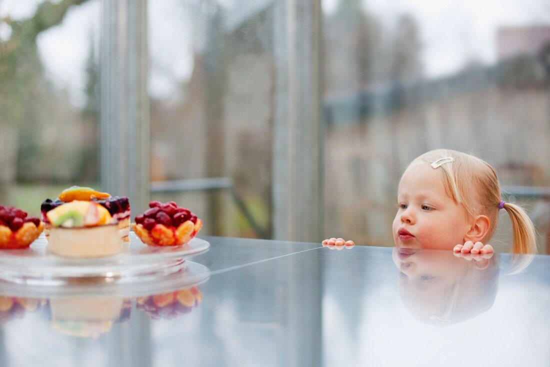 Toddler girl admiring fruit cakes