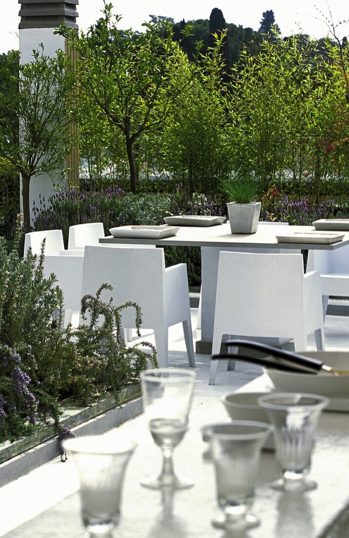 A dining table with chairs on a luxuriously planted roof terrace