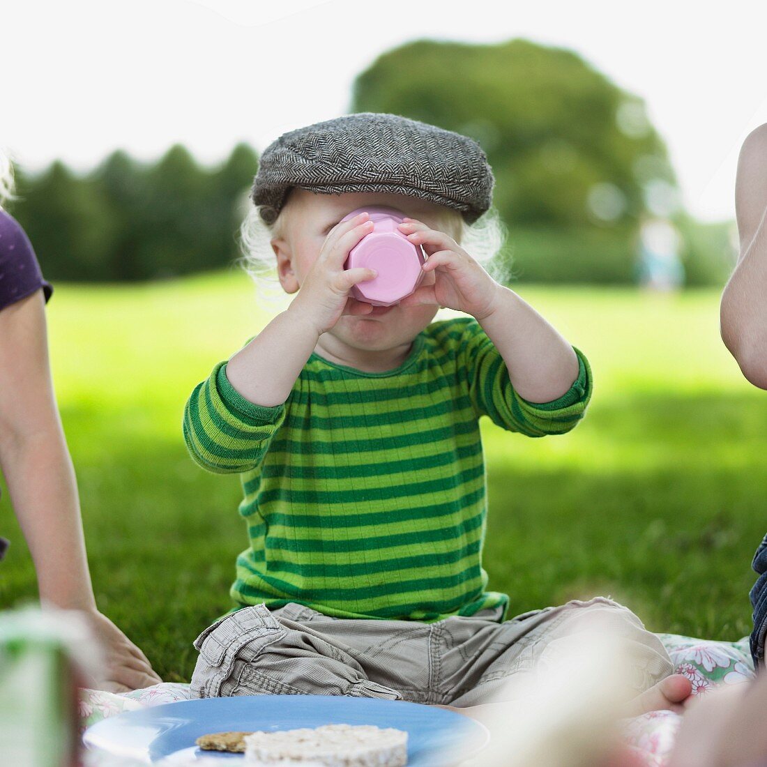 Kleiner Junge trinkt aus Plastikbecher beim Picknick