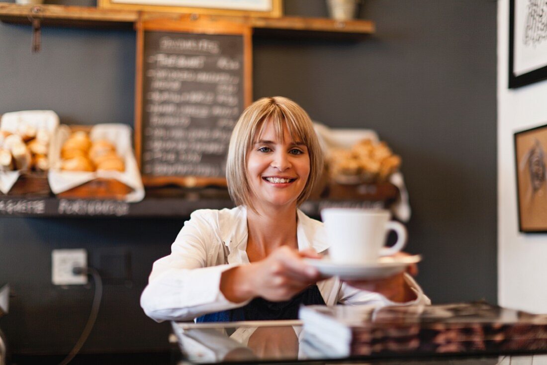 Frau serviert Kaffee im Café
