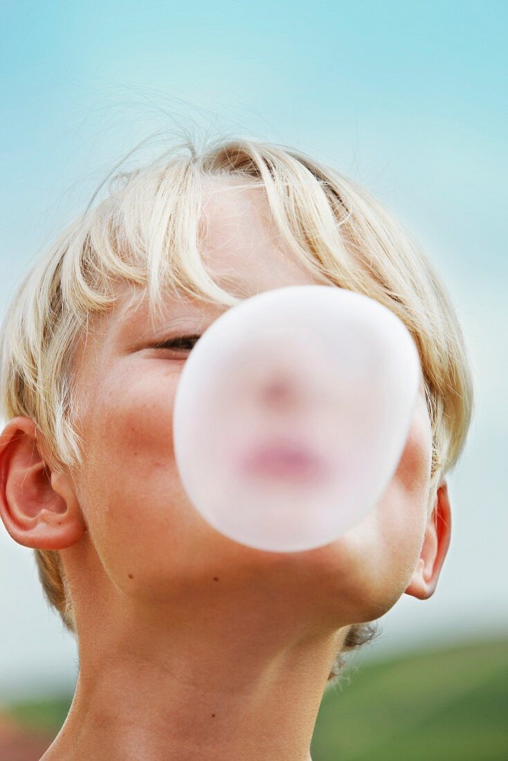 Smiling boy blowing bubble outdoors