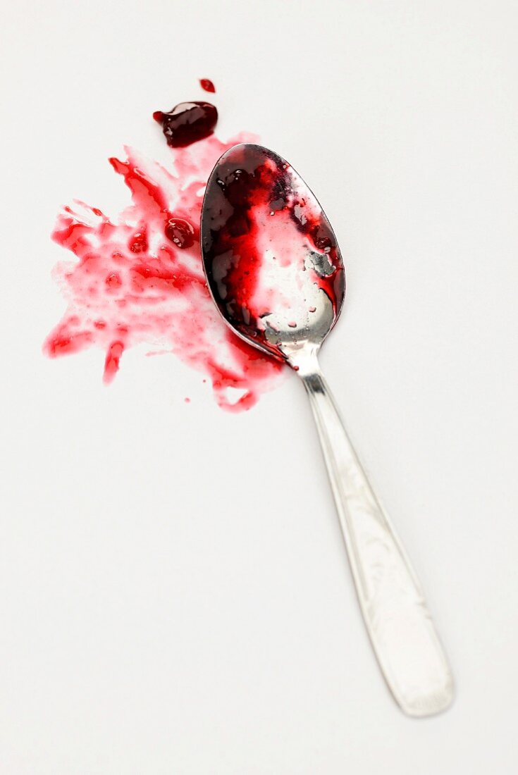 Cherry jam on a spoon leaving behind a stain